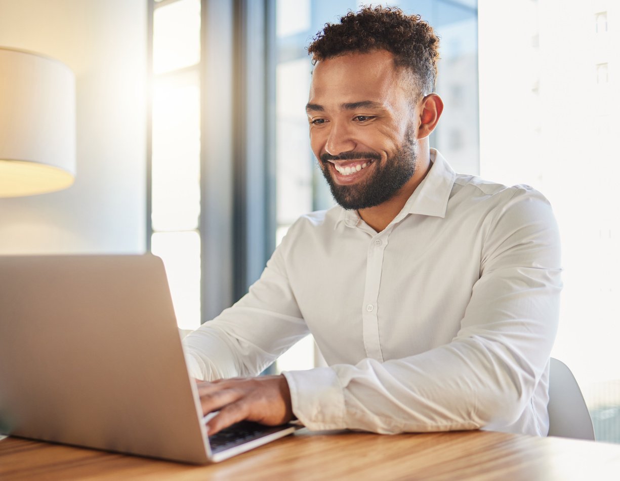 Happy Business Manager on Laptop Typing an Email Announcement for Success or Project Management Strategy Online in Office. Corporate Professional Smile for New Website Design at Company Startup